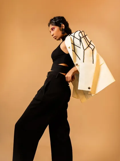A full-length lookbook shot showcasing a modern, tailored outfit. The model's pose highlights the embroidered jacket and wide-leg trousers.