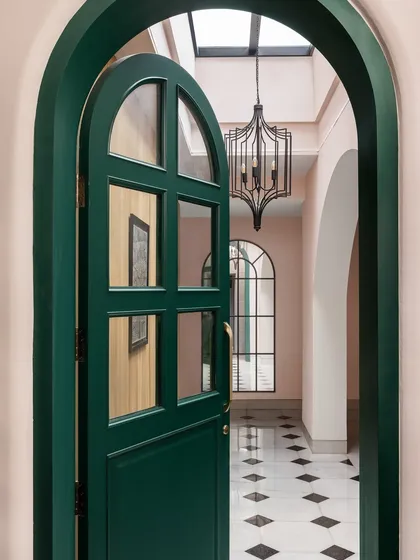 The entrance to the Quiet Ornate home makes a bold first impression. We chose a striking emerald green for the arched door, which opens into a skylit foyer with classic marble inlay floors, setting a tone of understated drama.
