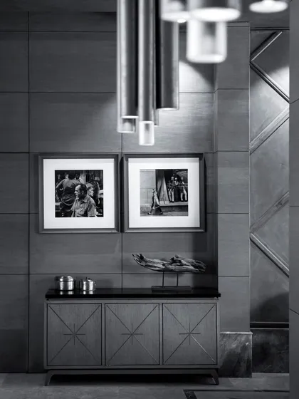 A monochrome view of a console area, highlighting the textures and forms. The custom sideboard with starburst marquetry is paired with black and white photography, showcasing our attention to curated details.