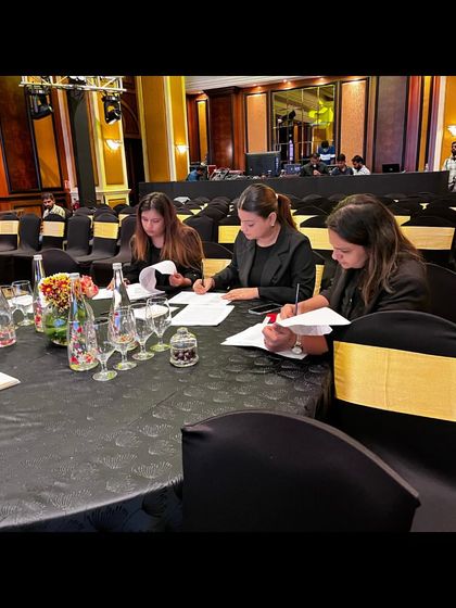 Our team reviewing scripts and schedules at our designated table during the TOI Social Impact Summit.