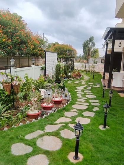 A beautiful view of a completed garden landscape. The combination of a natural lawn, irregular stone pavers for a rustic feel, and thoughtfully placed path lights creates a charming and functional backyard that invites you to take a stroll.