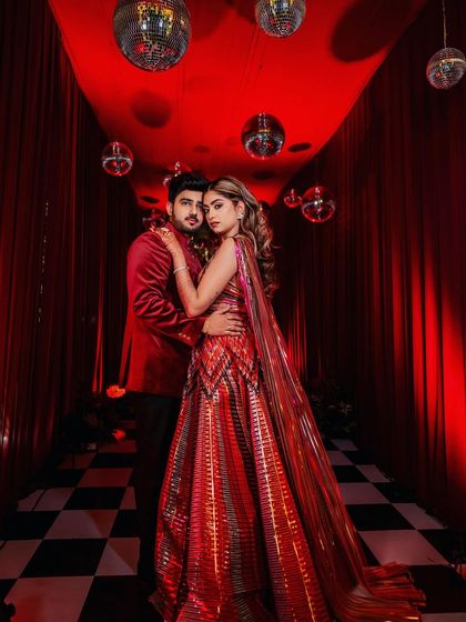 Something about red. This couple's portrait from their Sangeet is pure fire, with the dramatic red decor and disco balls creating a high-fashion, glamorous vibe.