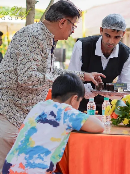 Our professional staff transforms dining into an experience of refined hospitality. Here, a server offers a tray of welcome drinks, demonstrating the warm and precise service we are known for.