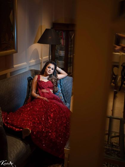 A glamorous bride in a sparkling red gown, relaxing on a couch. This shot has a relaxed yet high-fashion feel.