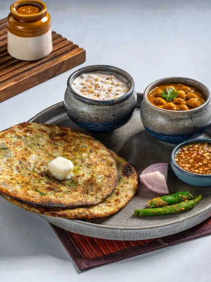 A rustic thali with missi roti, chana masala, and raita, shot for Gulab Sweets.