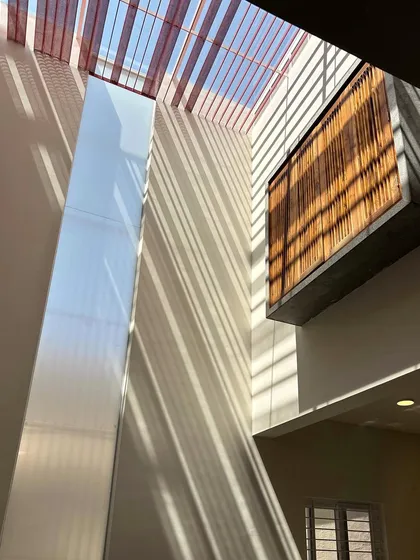 We are always exploring how light moves through a space. This is a glimpse of a work-in-progress skylight, where perforated red bands filter the direct sun, casting beautiful, linear shadows and filling the internal courtyard with soft, diffused light.