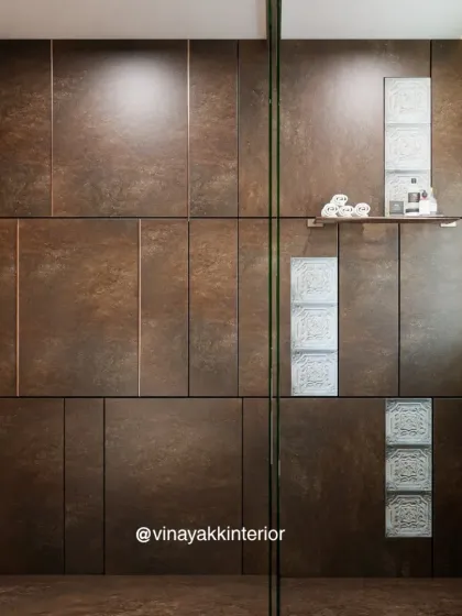 This shot highlights the beautiful contrast between the dark, textured wall panels and the intricate glass blocks inside the shower. The built-in niche provides convenient storage for toiletries.