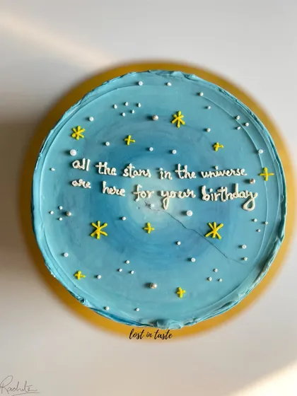 A dreamy birthday cake with a blue ombre buttercream base, decorated to look like a starry night sky with a hand-piped message.