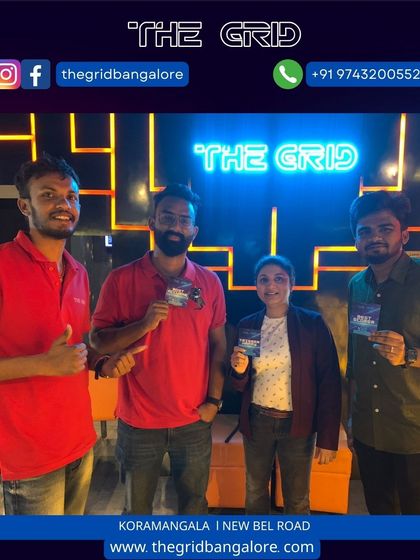 A group of winners proudly holding their prize cards in front of our neon logo.