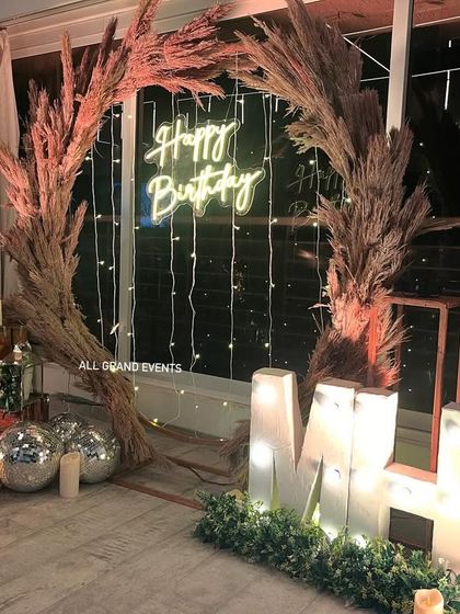 The rustic backdrop seen at night, with the neon sign, marquee letters, and fairy lights creating a warm and inviting glow.