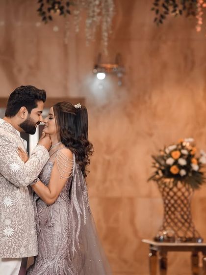 A tender moment between the couple, about to share a kiss during their engagement shoot. The warm, ambient lighting and floral arrangements create a deeply romantic and picture-perfect scene.