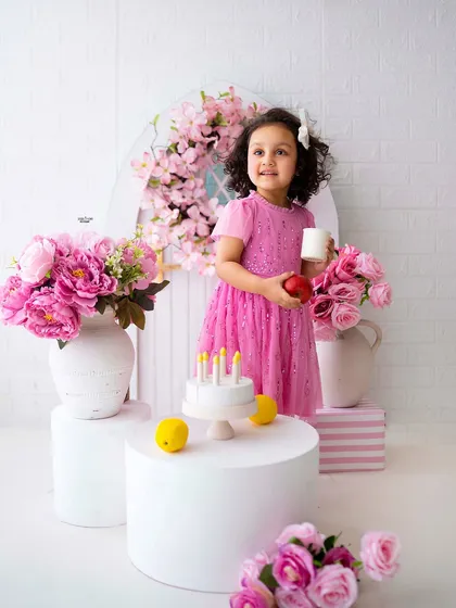 A pink-themed birthday setup for a sweet little girl, complete with a prop cake and beautiful flowers.