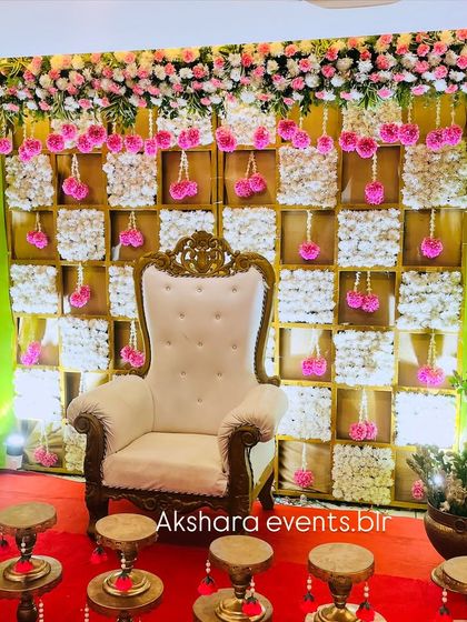 A beautiful pink and white themed backdrop for a baby shower. The checkerboard design is made with panels of white flowers, accented by hanging pink floral tassels for a delicate and feminine touch.