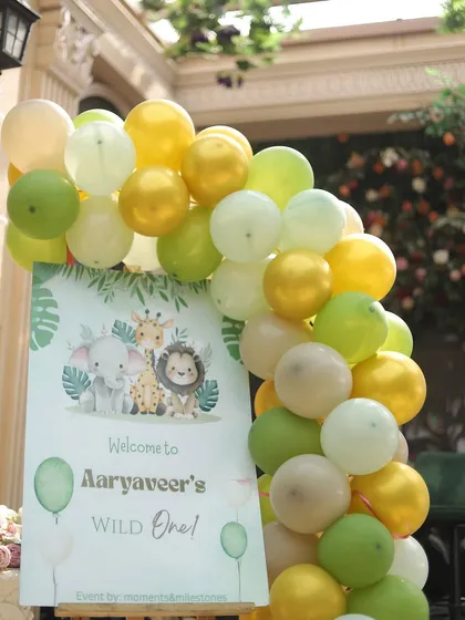 A simple and sweet welcome sign for Aaryaveer's party, framed by a balloon garland in soft, jungle-inspired colors.