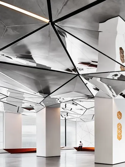 The interplay of light and reflection on the stainless steel ceiling panels. Integrated lighting within the black linear profiles ensures that the ceiling is both a functional and an aesthetic element.