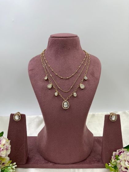 The Saanvi Royal Three-Layer Set. This delicate gold-plated set features three distinct chains with small pendants, offering a trendy, layered look in a single piece.
