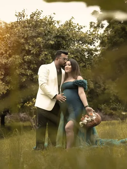 The dad-to-be joins for a loving portrait, placing a gentle kiss on her forehead. This is a perfect example of a romantic couple's maternity photo captured outdoors.