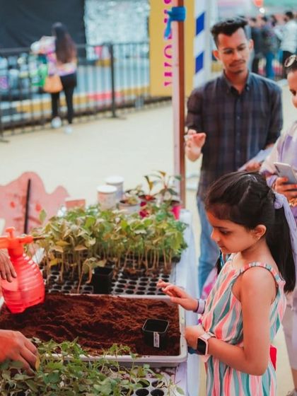 A plant potting station where a young girl learns to pot her own sapling. This is a wonderful, educational activity for environment-themed events.