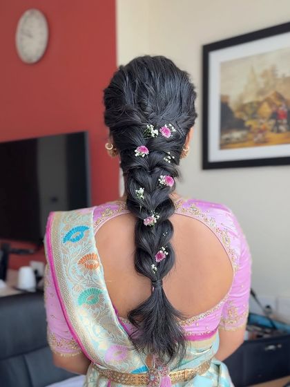 A close-up of a textured, messy braid adorned with small flowers. This romantic hairstyle is perfect for a bride or bridesmaid looking for something soft and elegant.