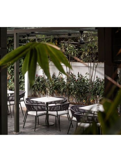 A glimpse of the serene outdoor seating at Kana Cafe, framed by bamboo leaves. The design is a testament to the harmonious relationship between urban architecture and natural elements.