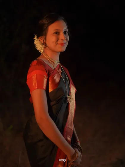 A simple and elegant side profile portrait taken at night. The soft lighting highlights the subject's features and the traditional 'gajra' in her hair, creating a serene mood.