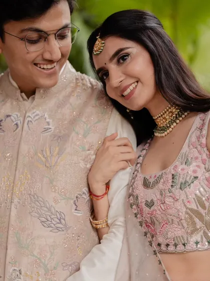 A sweet, candid moment between the couple. The bride's soft pink lehenga and the groom's classic attire are perfect for a graceful and elegant engagement ceremony.