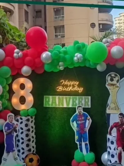 A football-themed birthday party for Ranveer, an 8-year-old fan. The outdoor setup includes a goal-post backdrop, cutouts of famous football players, and a balloon arch in team colors.