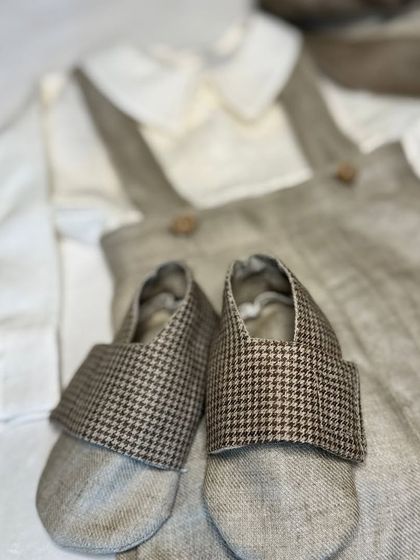 A close-up of the handmade soft shoes and linen-blend fabric from our vintage-inspired beige suit set for boys.