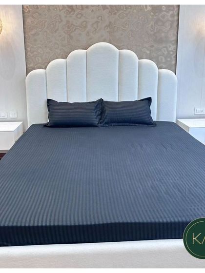 A modern bedroom setting featuring a bed with a scalloped, channel-tufted headboard in clean white. Paired with minimalist nightstands and elegant pendant lights, this design creates a chic and restful sanctuary.