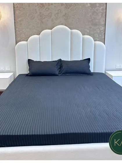 A modern bedroom setting featuring a bed with a scalloped, channel-tufted headboard in clean white. Paired with minimalist nightstands and elegant pendant lights, this design creates a chic and restful sanctuary.