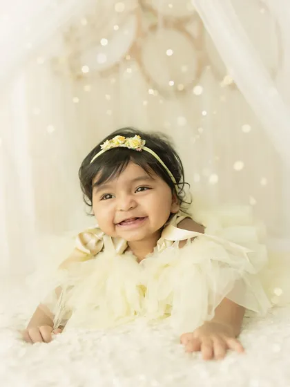 A bright, joyful smile from the baby, captured in a soft and ethereal setting.