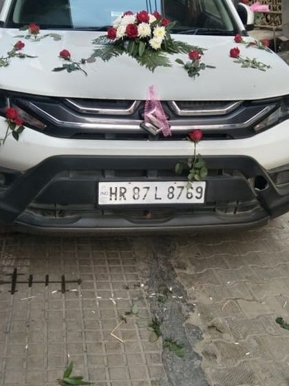 A minimal decoration on a white Brezza, featuring a single bouquet on the bonnet and a few scattered roses.