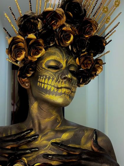 This image shows the full scope of the golden skull fantasy look, including the body paint and elaborate headwear.