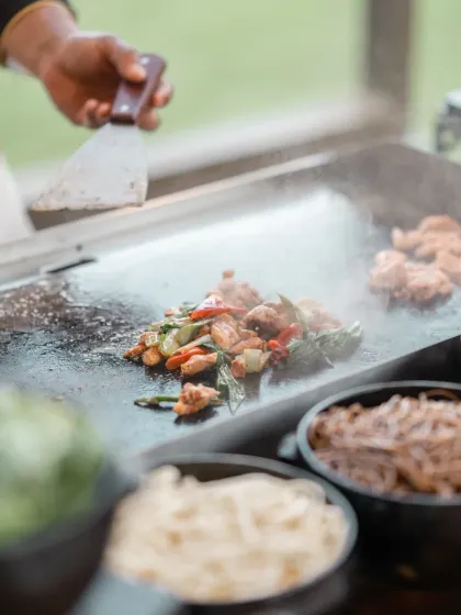 A close up of a chef preparing food on a teppanyaki grill, capturing the sizzle and action of a live cooking station.