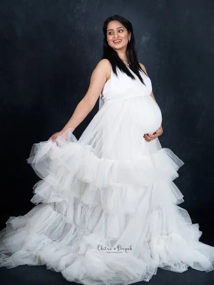 A simple and happy portrait in a white ruffled gown. The dark background makes the dress appear even more bright and angelic.