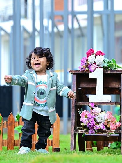 A joyful one-year-old boy in an outdoor setting, celebrating his first birthday with a smile.