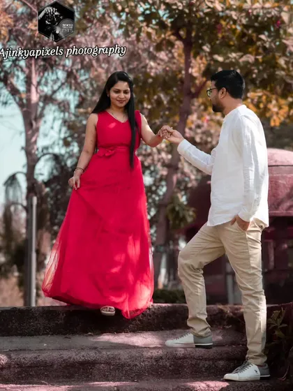 A lovely shot of the couple walking down a set of rustic stairs in a park. His guiding hand and her elegant red dress create a fairytale-like moment.