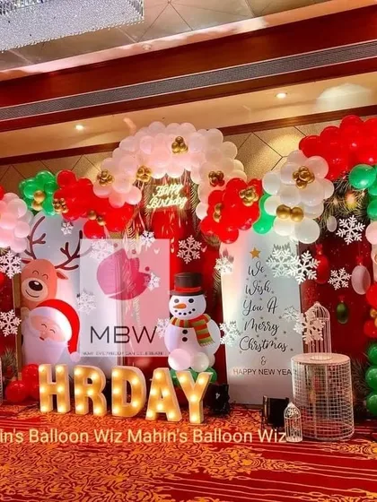 A festive Christmas-themed birthday party. The stage is decorated in classic red, green, and white, with props like Santa, a snowman, reindeer, and snowflake cutouts.