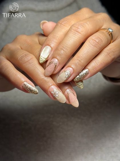 Gold that glows and elegance that shows. This set combines full gold glitter nails, hand-painted florals, and abstract gold chrome accents.