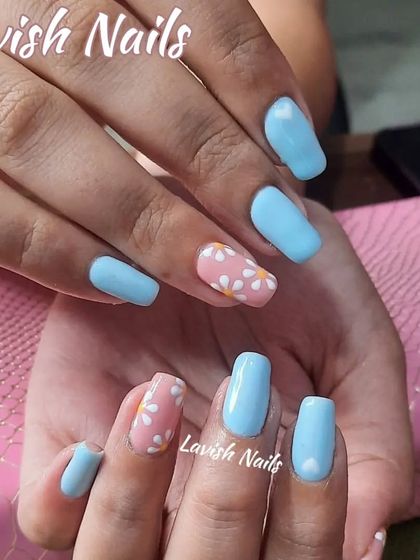 A cute and summery design with light blue nails and a pink accent nail covered in tiny white daisies.
