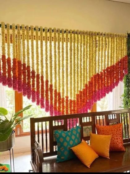 A beautiful and simple decoration for a home function. A curtain of marigold and tuberose strings is arranged in a V-shape, creating a perfect backdrop for a swing or seating area.