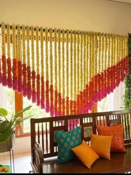 A simple and beautiful decoration for a pooja or small ceremony at home. A curtain of marigold and tuberose strings hangs behind a traditional wooden swing, creating a perfect sacred corner.