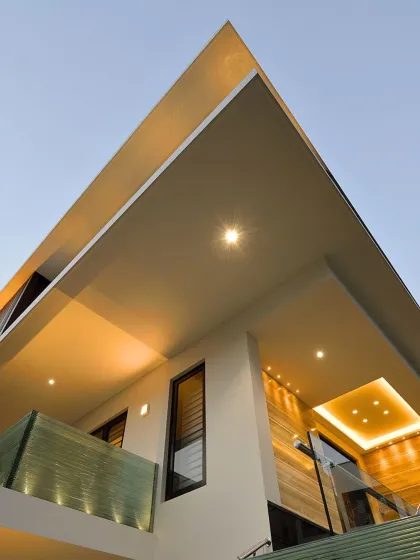 Crafting timeless designs with precision and innovation. This low-angle view highlights the sharp, clean lines of the roof and the warm, inviting glow of the exterior lighting.