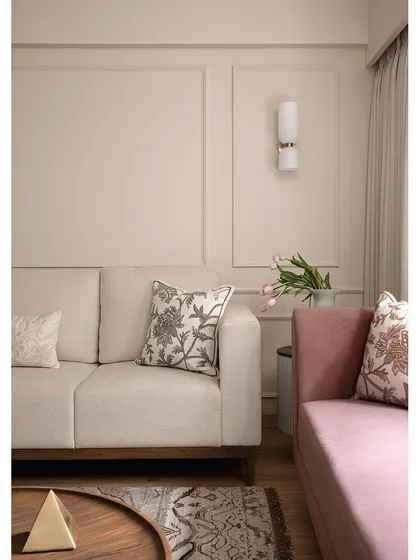 The living room of "Apartment 222" uses a soft, neutral palette to create a calming atmosphere. The pink sofa adds a gentle touch of color, while the embroidered cushions and wall sconces provide layers of detail and warmth.