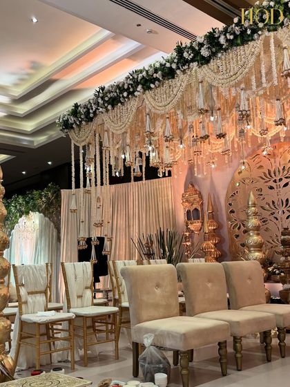 A side view of the grand stage during setup, showing the layers of detail, from the chair styling to the intricate ceiling installation.