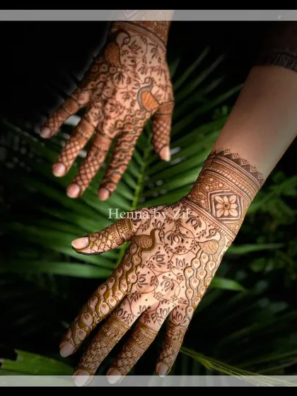 An elegant bridal design with a mix of bold and delicate elements. The wrist cuff features a band of flowers, while the palm is adorned with a flowing pattern of vines and peacocks.