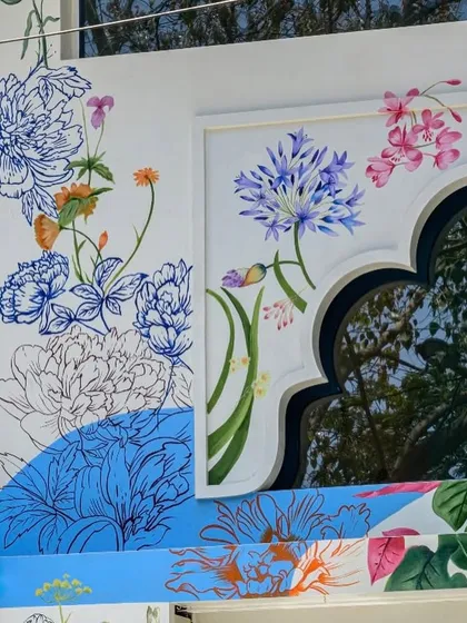 A detail of the hand-painted facade for 'Kath n Ghat', inspired by Maharashtrian foliage. The artwork combines colorful painted sections with delicate blue line drawings, creating a rich, layered effect.