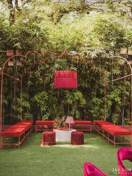 A bold and modern lounge setup for the "Red Affair," featuring minimalist red metal-frame seating against a backdrop of natural bamboo.