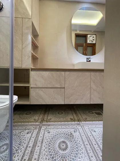 This bathroom features a unique patterned tile on the floor, which adds personality and visual interest. The floating vanity is finished in a light marble laminate, keeping the space feeling bright.