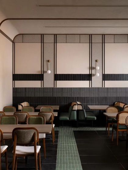 We created different zones within the large restaurant space. This section uses clean wall paneling and a mix of seating types, including custom cafe seating solutions, to offer a varied dining experience under soft, ambient lighting.